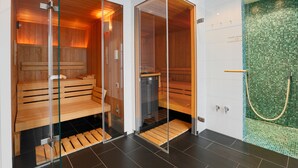 Two sauna rooms with glass doors, wooden benches, and a tiled floor. - Privathotel alte mühle (Weyhausen)