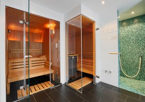 Two sauna rooms with glass doors, wooden benches, and a tiled floor.