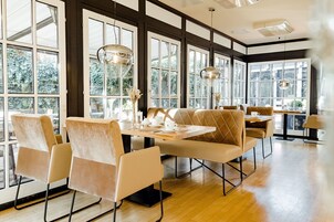 A spacious dining area with large windows, modern furniture, and pendant lighting.