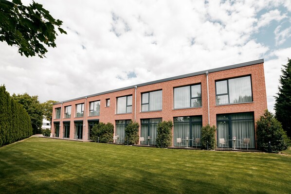 A modern brick building with large windows and a well-maintained lawn. - Privathotel alte mühle (Weyhausen)