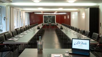 Ein Konferenzraum mit einem langen Tisch, Stühlen und einem Laptop, auf dem