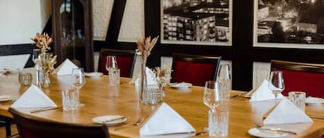 A dining table set for four with white napkins, clear glassware, and decorative vases.
