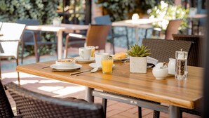 A dining table set with breakfast items, including a plate of food, a glass of orange juice, and a small potted plant. - Privathotel alte mühle (Weyhausen)