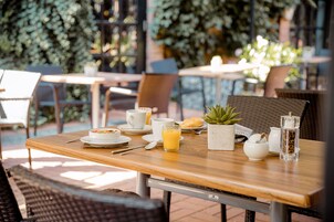 A dining table set with breakfast items, including a plate of food, a glass of orange juice, and a small potted plant.