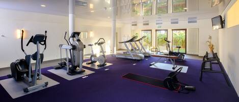 Una palestra con diverse macchine cardio, una panca per pesi e un tappetino da yoga.