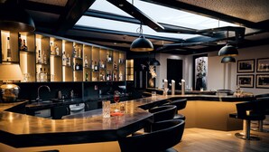 A modern bar area with a central island, bar stools, and a wine rack. - Privathotel alte mühle (Weyhausen)