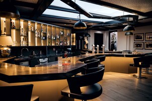 A modern bar area with a central island, bar stools, and a wine rack.