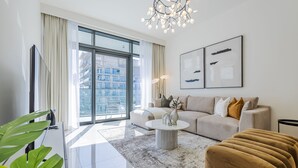 A modern living room with a large window, a sofa, a coffee table, and a chandelier.