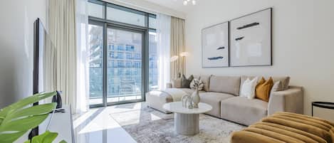 A modern living room with a large window, a sofa, a coffee table, and a chandelier.