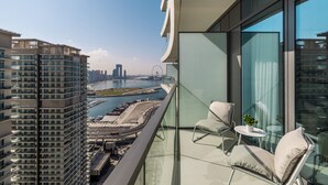 A high-rise building with a glass balcony overlooking a marina and city skyline.
