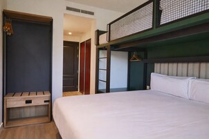Una habitación de hotel con cama, un banco de madera, un armario y una percha.