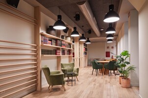 Eine moderne Bibliothek mit Holzbögen, grünen Sesseln und einem Holztisch.