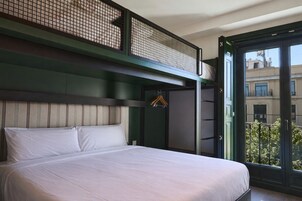 Ein Schlafzimmer mit Bett, Kleiderhaken und einem Balkon mit Blick auf Gebäude.