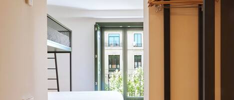 A modern bedroom with a bunk bed, wooden floor, and a view of the outside balcony.