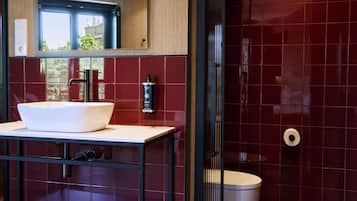 A modern bathroom with a large mirror, a white sink, and a toilet.