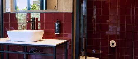 Een moderne badkamer met een grote spiegel, een wit wastafel en een toilet.
