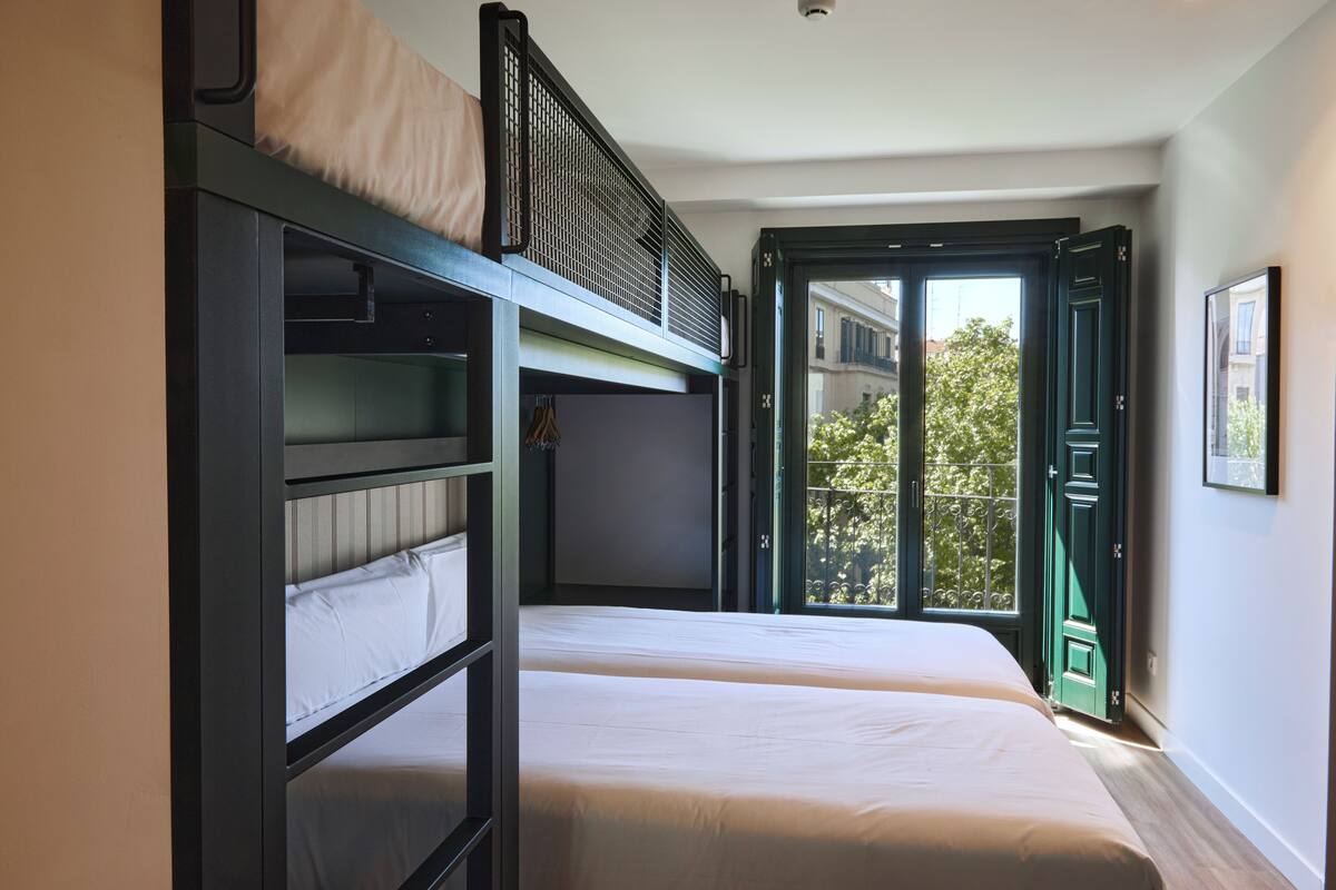 A room with bunk beds, a balcony, and a door leading outside.