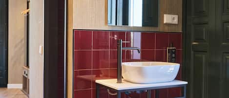 Un baño moderno con un espejo grande, un lavabo blanco y un perchero para toallas.