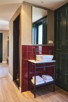 Ein modernes Badezimmer mit einem großen Spiegel, einem weißen Waschbecken und einem Handtuchhalter.
