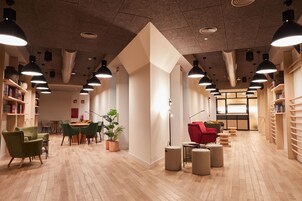Una biblioteca moderna con pavimenti in legno, scaffali e zone salotto confortevoli.