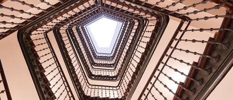 Eine Wendeltreppe mit einem Oberlicht in der Mitte, umgeben von einem Metallgeländer.