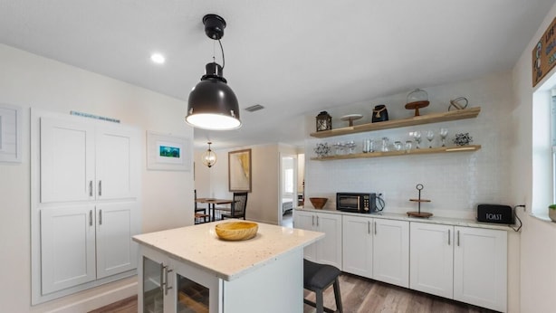 Una cocina moderna con armarios blancos, una isla central, microondas y tostadora.