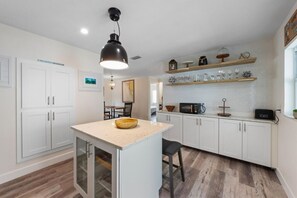 A modern kitchen with white cabinets, a central island, a microwave, and a toaster. - Sandy Cheeks: Ground-level home with plunge pool. Close to pier, park, & Bay! (Anna Maria)
