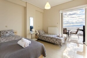 A hotel room with two beds, a balcony with a table and chairs, and a view of the sea.