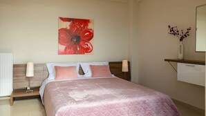 Une chambre d’hôtel avec un lit, des lampes de chevet, une table de chevet, une étagère murale ornée d’un vase et un grand tableau représentant des fleurs.