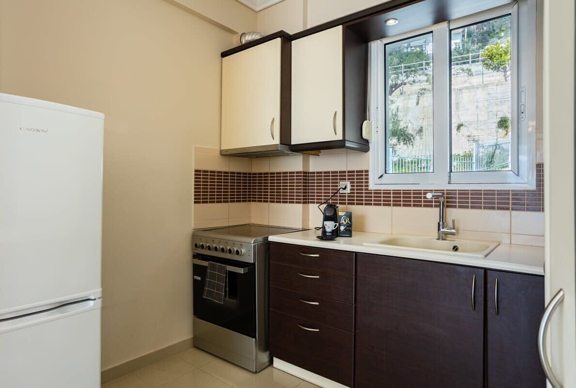 A compact kitchen with a built-in oven, a coffee maker, and a window with a view of a hillside.