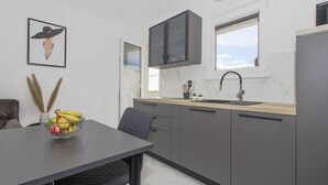 A modern kitchen with grey cabinets, a black countertop, and a window above the sink.