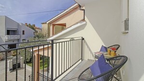 A balcony with a table and chairs, a small staircase, and a view of neighboring buildings.
