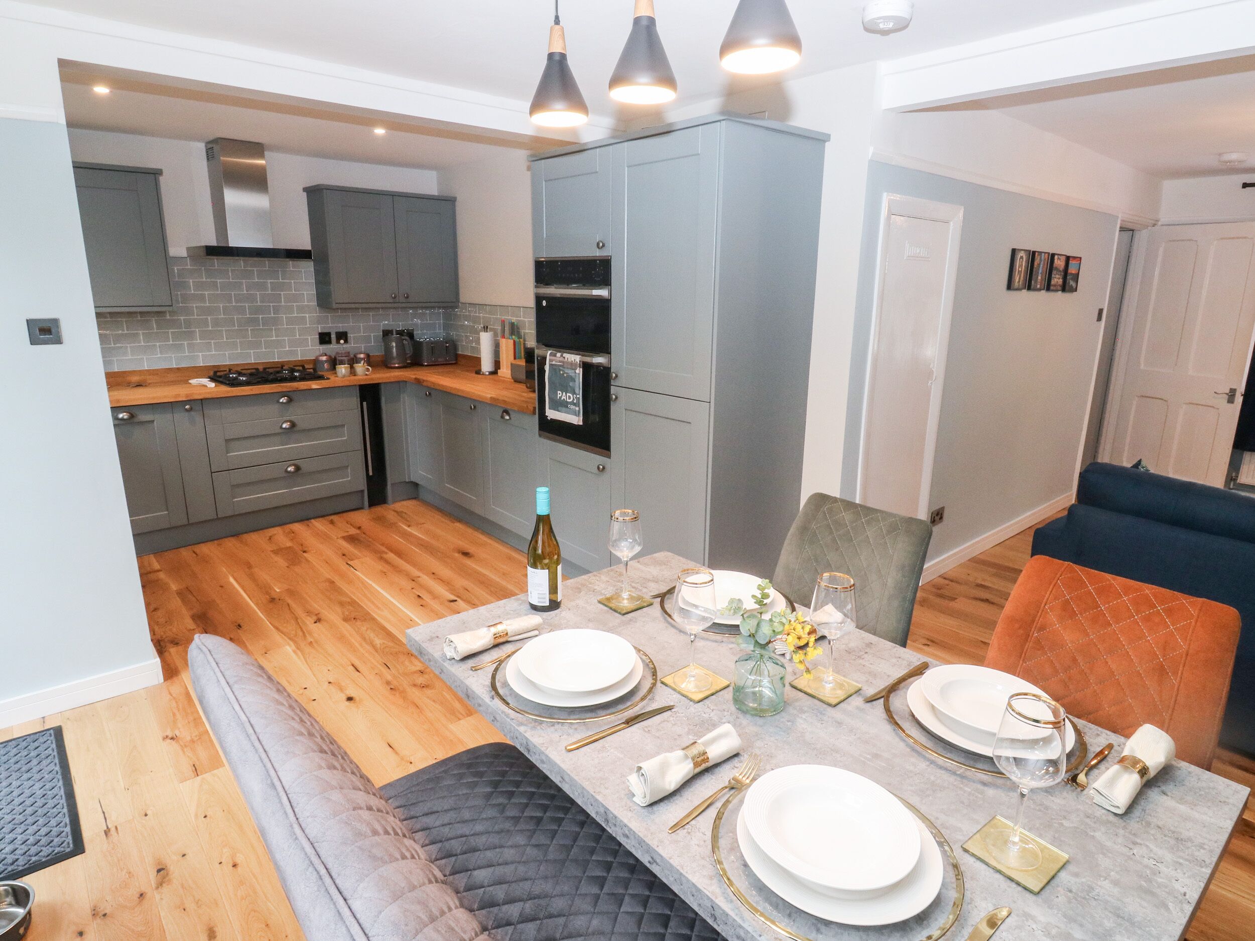 A modern kitchen with grey cabinets, a wooden countertop, and a dining area set for a meal.