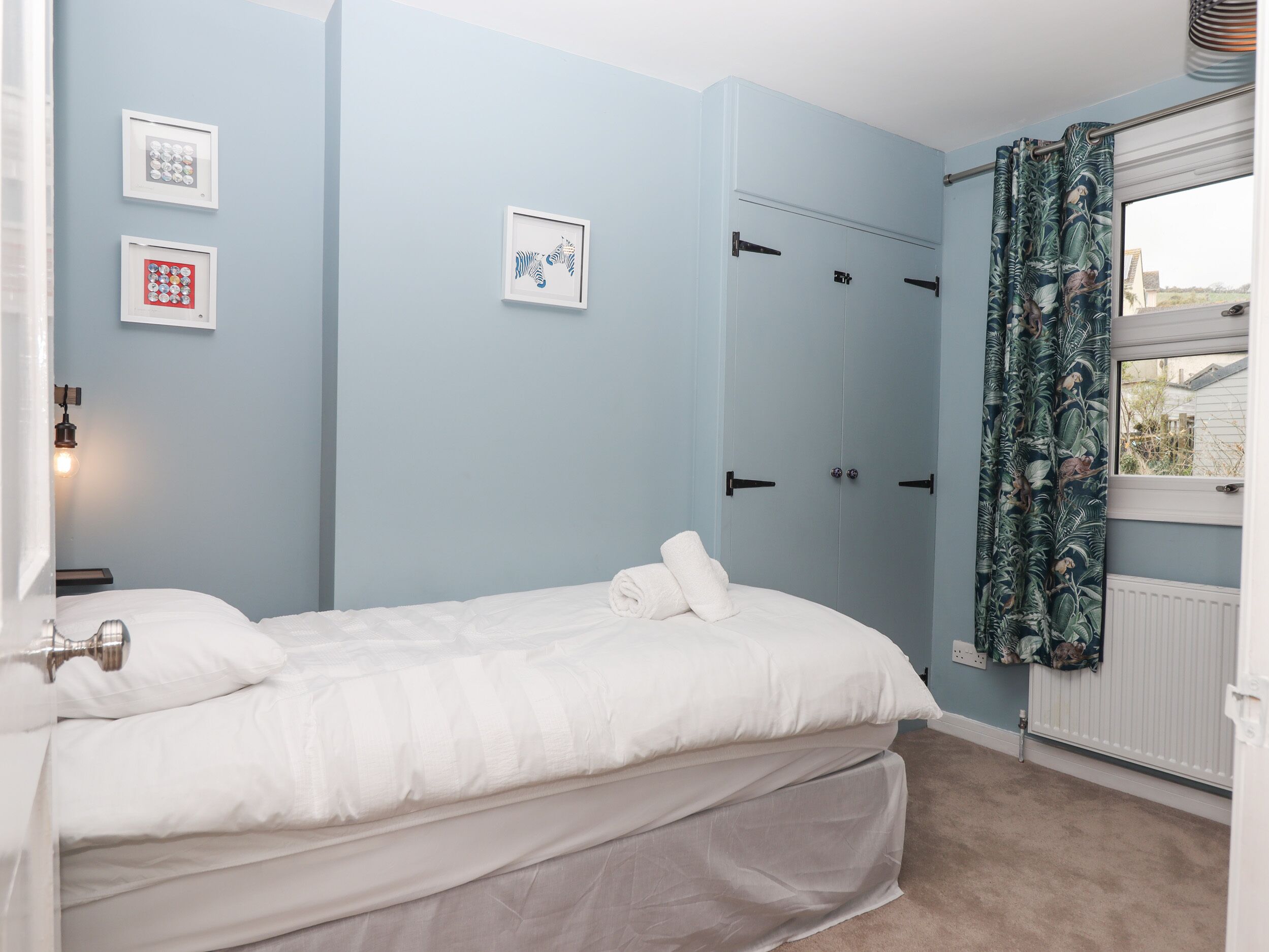 Quarto com cama, guarda-roupa e janela com cortinas.