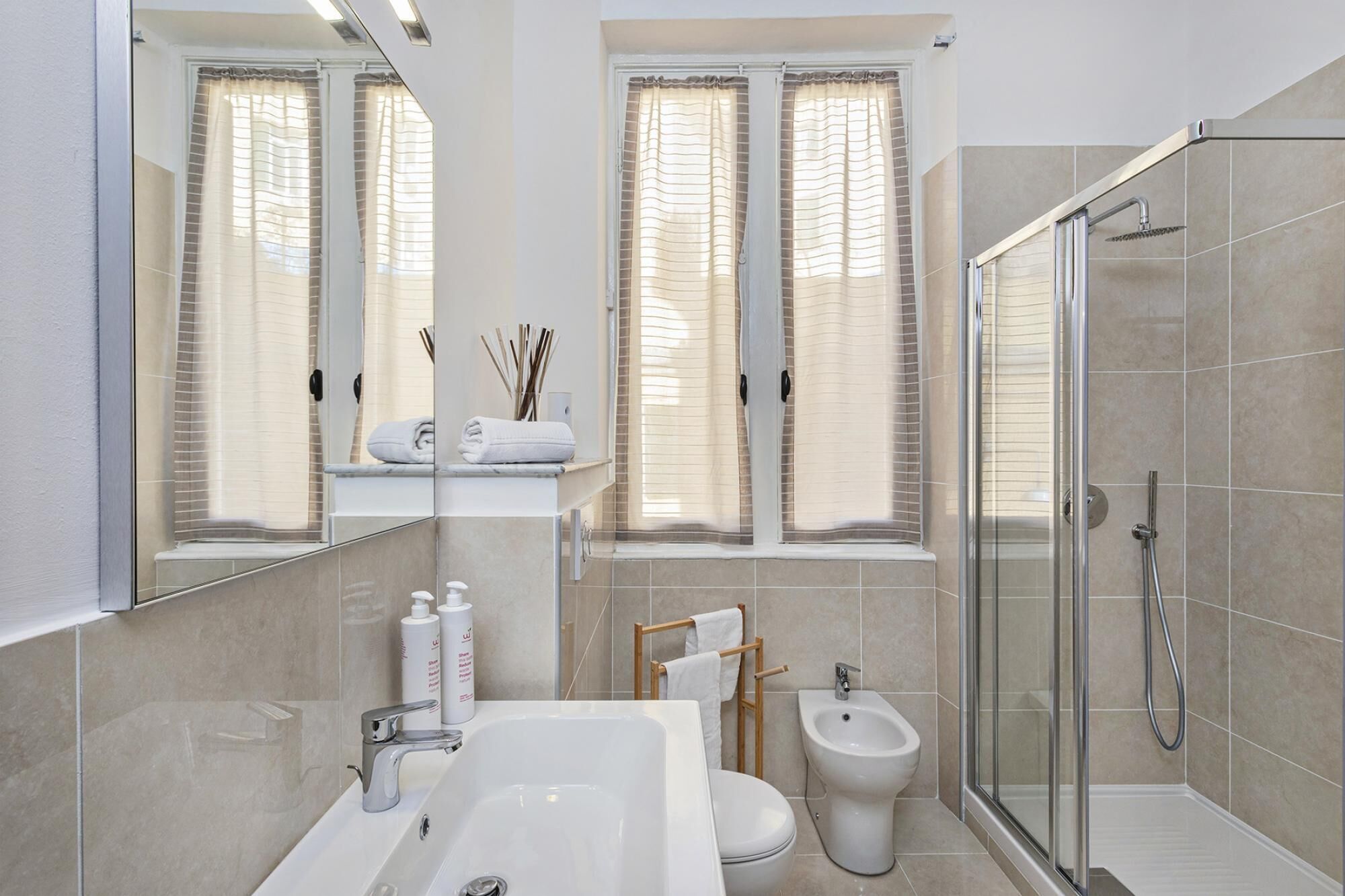 Ein modernes Badezimmer mit großem Spiegel, einer Badewanne, einer Toilette, einem Bidet und einer Duschkabine.