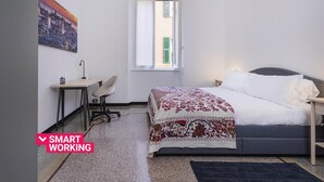 Un dormitorio con cama, escritorio, silla y ventana.