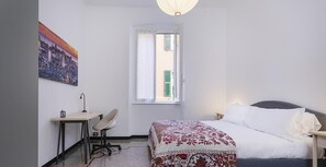 Un dormitorio con cama, escritorio, silla y ventana.