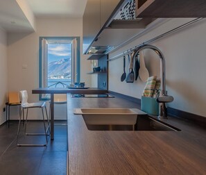 Enjoy a scenic view of the mountains from this kitchen, featuring a sink, wooden countertop, and ample space for dining or working.