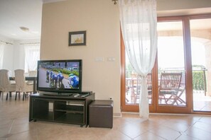 Relax in this living room with a TV, sliding glass door to an outdoor area, and a comfortable seating space.