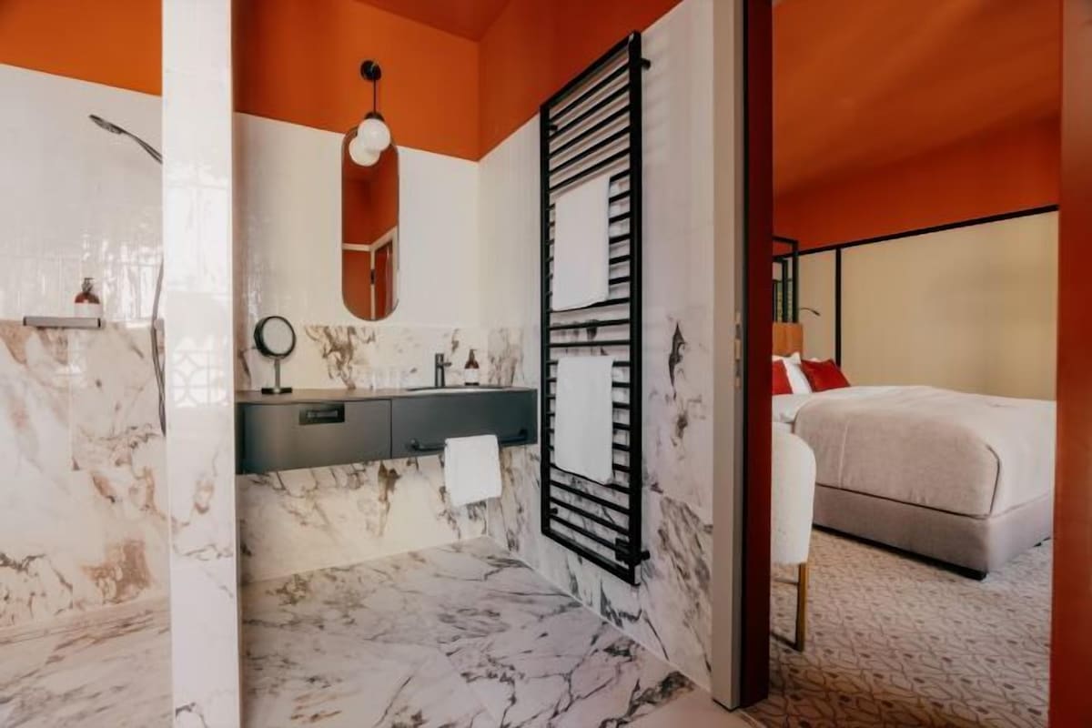 Une salle de bain avec un sol en marbre, un lavabo, un miroir et un porte-serviettes.