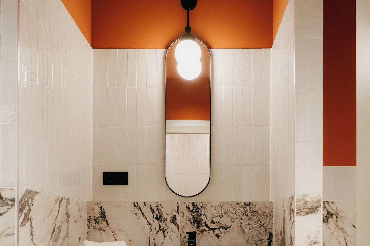 Une salle de bain avec un lavabo en marbre, une serviette suspendue à un porte-serviettes et un miroir au-dessus du lavabo.