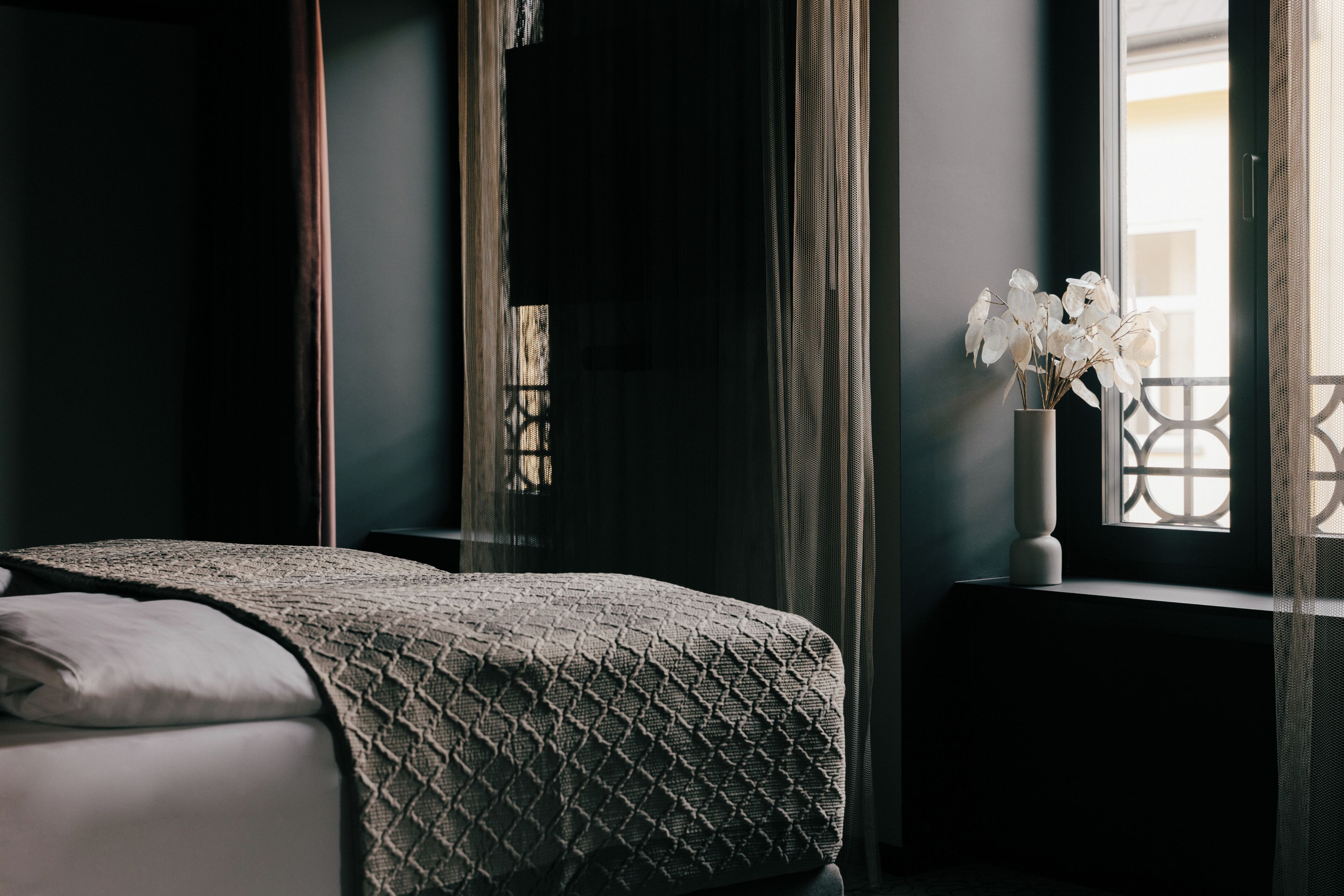 Une chambre à coucher avec un lit, une fenêtre donnant sur un beau paysage et un vase rempli de fleurs.