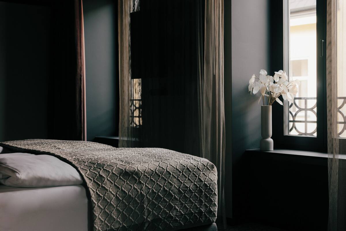 Een slaapkamer met een bed, een raam met uitzicht en een vaas met bloemen.