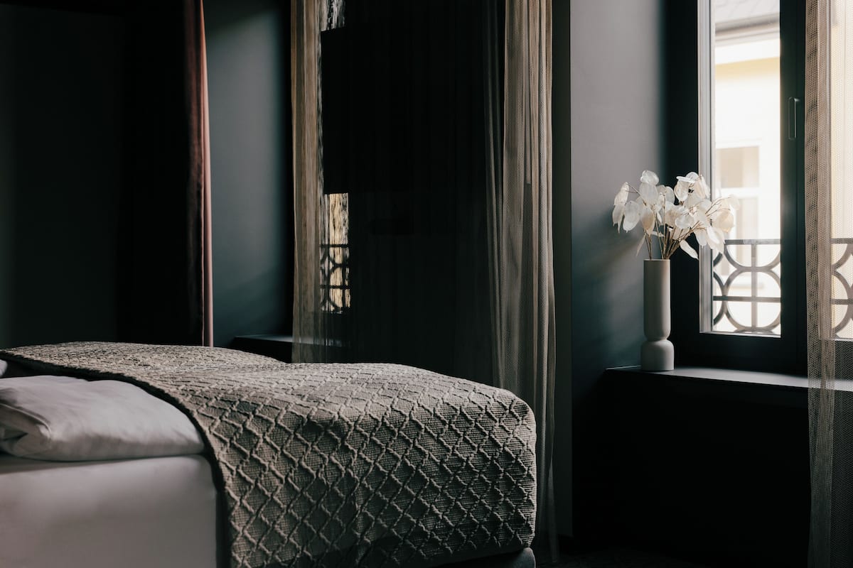 Une chambre à coucher avec un lit, une fenêtre donnant sur un beau paysage et un vase rempli de fleurs.