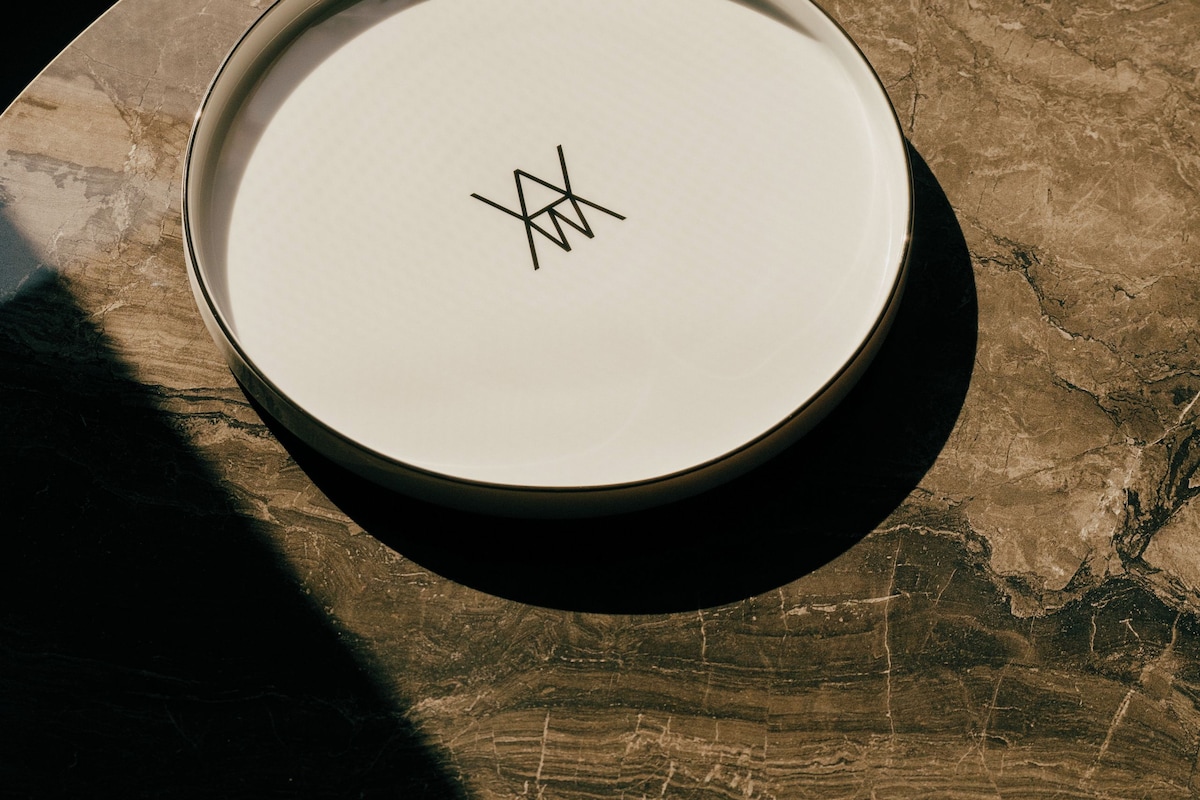 Une assiette blanche ornée d’un motif noir, posée sur une table ronde dont le plateau est de couleur marbrée.