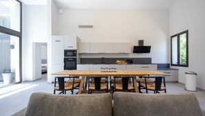 Een moderne keuken met een eethoek, met een grote tafel, stoelen en uitzicht op de omgeving.