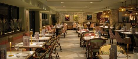 A restaurant with multiple dining tables, chairs, and hanging light fixtures.