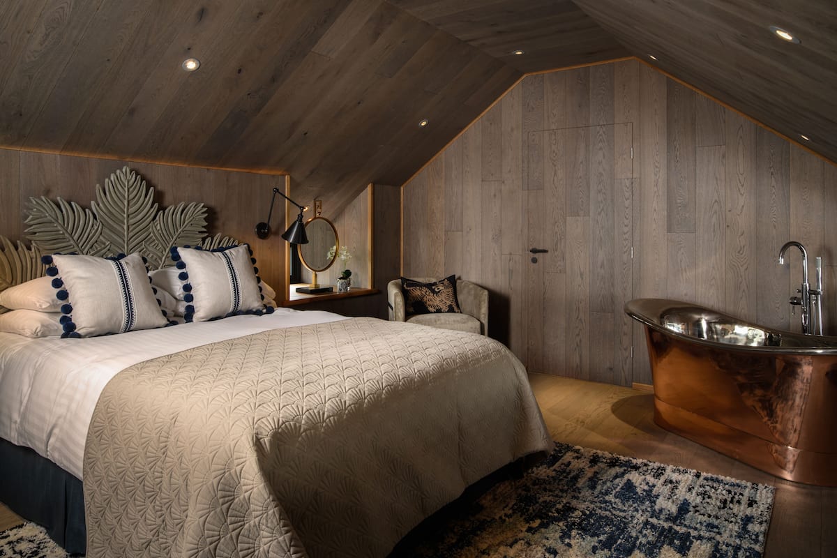 Un dormitorio con una cama grande, una bañera de cobre y un techo de madera.