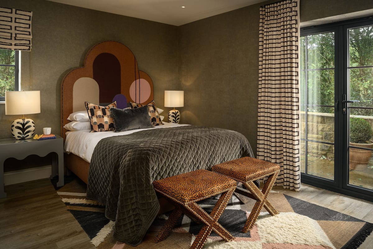 Un dormitorio con cama, dos mesitas de noche, una ventana con cortinas y vistas al exterior.