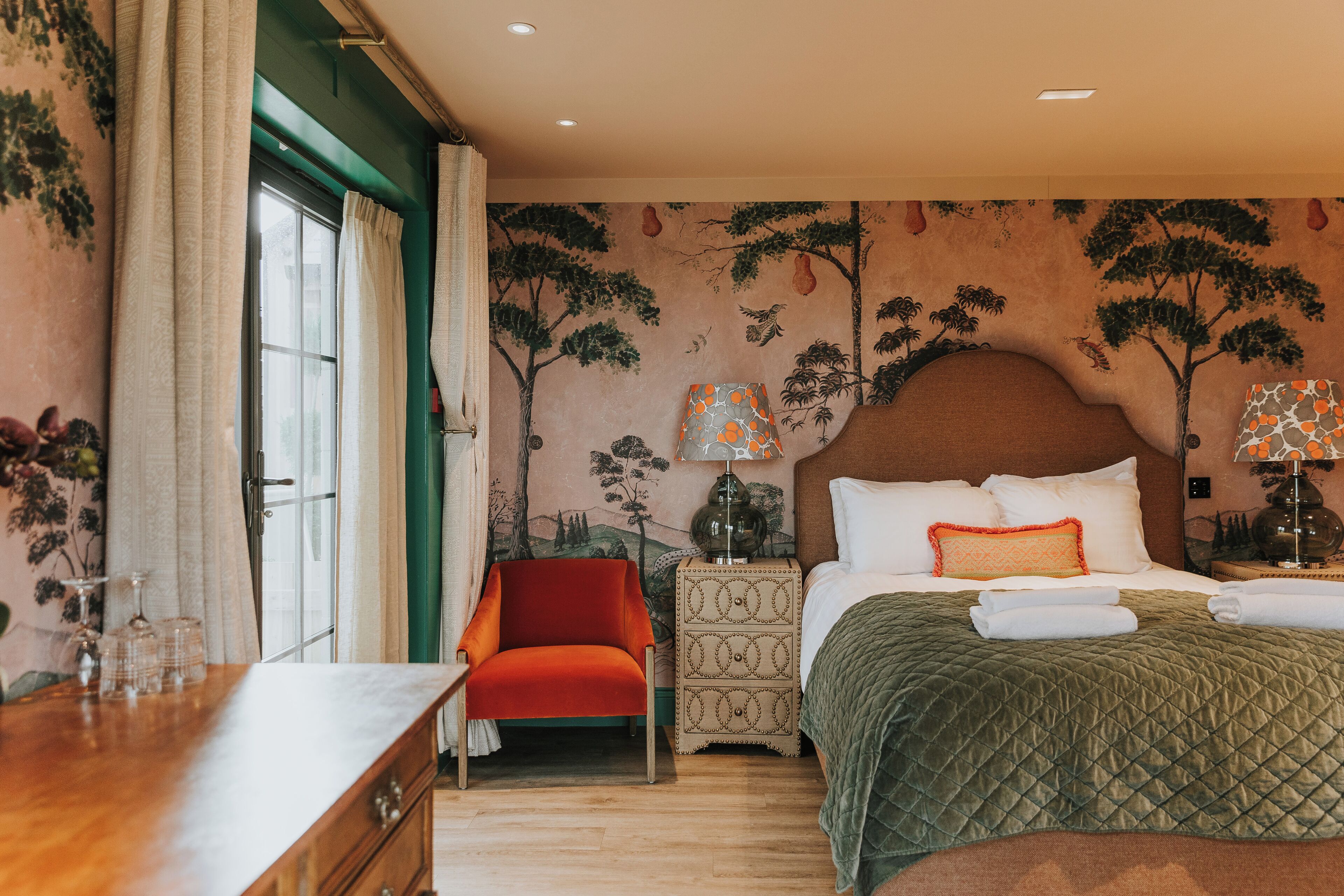 A hotel room with a bed, a nightstand, a chair, and a dresser.